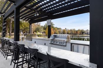 a bar with chairs and a grill on a patio